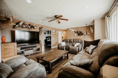 Cozy living room with a large TV, comfortable sofas, and mounted animal trophies on the walls.