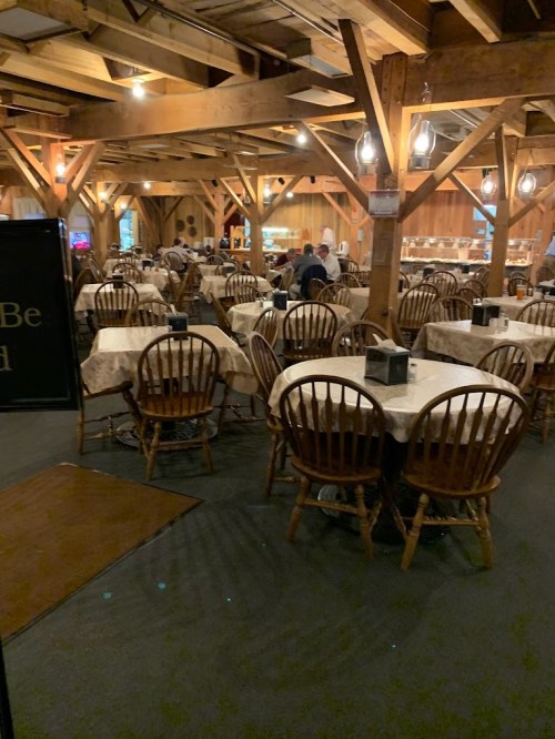Interior of a rustic restaurant with wooden beams, empty tables, and chairs, creating a cozy atmosphere.