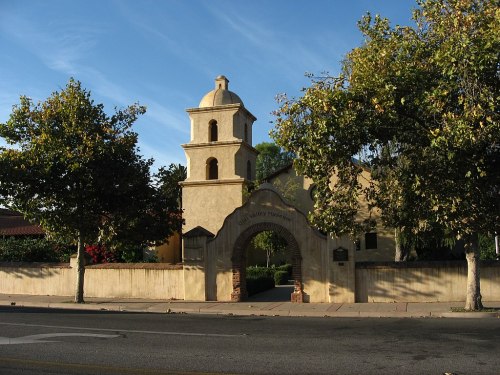 Historic building with a bell tower, surrounded by trees and a clear blue sky.