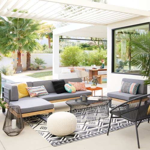 A stylish outdoor living space with modern furniture, plants, and a cozy seating area under a pergola.
