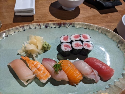 A plate of assorted sushi, including nigiri and rolls, garnished with wasabi and pickled ginger.