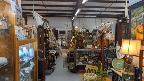 A bustling antique shop filled with various vintage items, furniture, and decor lining the aisles.