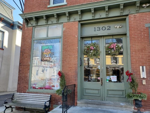 A charming bakery storefront with festive wreaths, a "Bakery" sign, and a bench outside.
