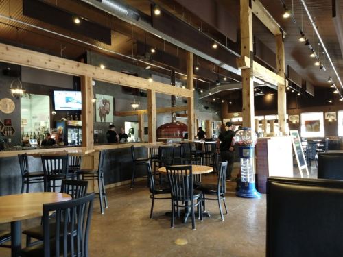 Interior of a restaurant with wooden beams, tables, and a bar area, featuring a warm, inviting atmosphere.