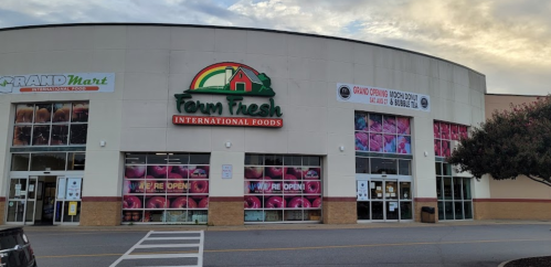 Exterior of Farm Fresh International Foods store with colorful signage and "We're Open" displayed on the windows.