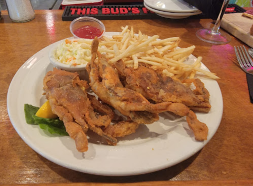 A plate of fried crab, served with fries, coleslaw, and a side of dipping sauce.