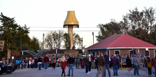 A crowd gathers near a large, golden lamp post and a red-roofed building during an outdoor event.