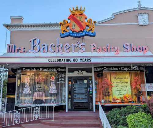 A charming pastry shop with a colorful sign celebrating 80 years, featuring baked goods in the window display.