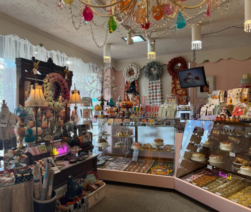 A colorful shop filled with decorative sweets, cakes, and unique gifts, featuring a chandelier and festive decor.