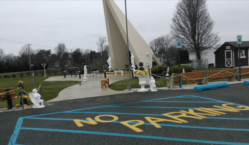 A parking area with a "No Parking" sign, surrounded by decorative statues and a tall monument in the background.