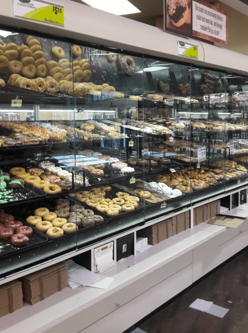 A display case filled with various donuts, showcasing colorful toppings and different flavors in a bakery.