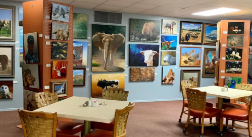 A cozy dining area with tables surrounded by walls adorned with various animal paintings and photographs.