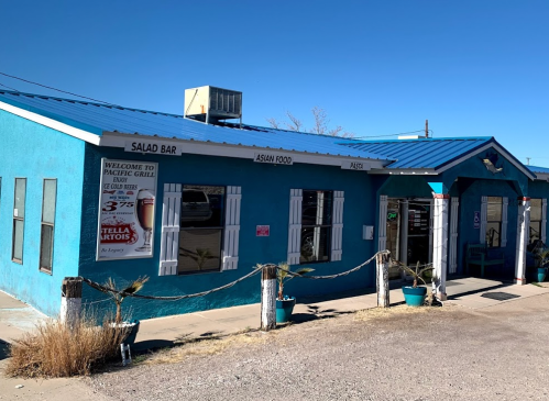 A bright blue building with a salad bar and Asian food sign, featuring a blue roof and desert landscape.