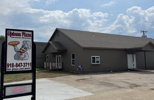 A pizza restaurant with a sign reading "Uptown Pizza" in Barnsdall, Oklahoma, under a cloudy sky.