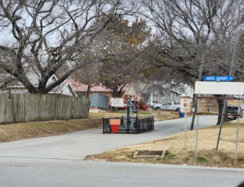 A quiet street with bare trees, a parked lift, and a sign for "Arena Street" in a residential area.