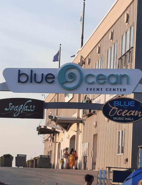 Signage for Blue Ocean Event Center and Blue Ocean Music Hall, with a view of a building and people walking.
