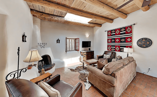 Cozy living room with wooden beams, a fireplace, and southwestern decor, featuring a TV and comfortable seating.