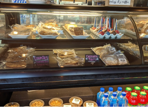 Display case filled with various baked goods, including cookies, dessert bars, and chocolate treats.
