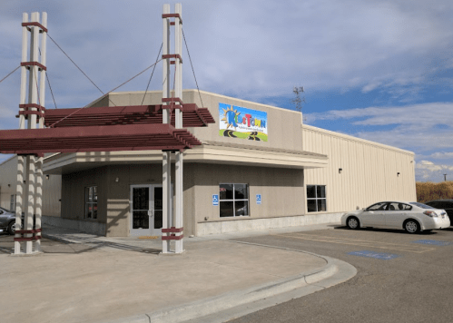 Exterior of a building with a colorful sign reading "Playtown," featuring a parking area and clear blue sky.