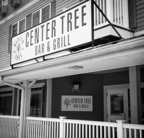 Black and white image of the Center Tree Bar & Grill sign on a building with a porch railing.