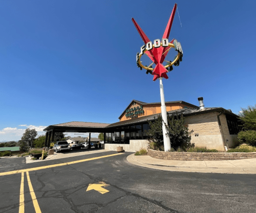A retro-style restaurant with a large "FOOD" sign and a curved driveway under a clear blue sky.