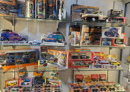 A display of various toy cars and trucks on glass shelves, featuring colorful packaging and different models.