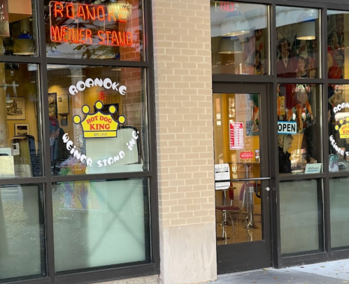 Exterior view of Roanoke Hot Dog King, featuring a neon sign and large windows with an open sign.