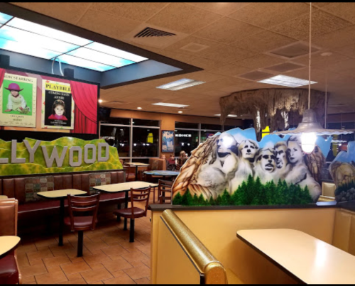 Interior of a fast-food restaurant featuring a Hollywood theme with murals and empty tables.