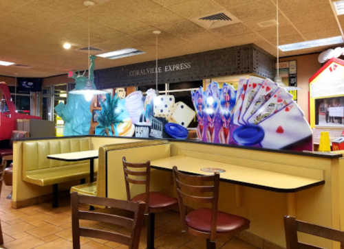 Interior of a fast-food restaurant featuring colorful murals and empty seating.