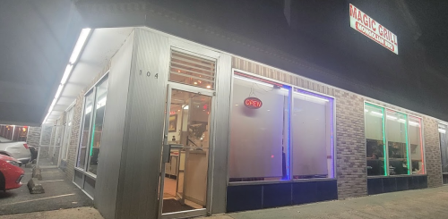 Exterior of Magic Grill restaurant at night, featuring an "OPEN" sign and colorful lighting.