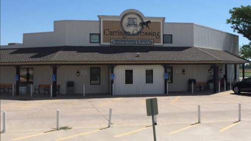 Exterior of Carriage Crossing Restaurant & Bakery, featuring a sign and accessible parking spaces under a clear blue sky.