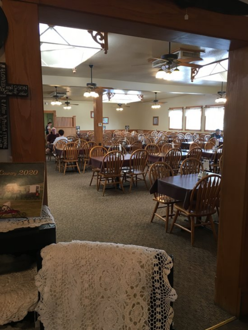 A spacious dining area with wooden chairs and tables, featuring a cozy, rustic decor and bright lighting.