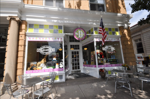 A colorful storefront with a sign reading "Praline's" featuring outdoor seating and an American flag.