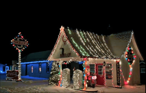 A cozy building adorned with colorful Christmas lights, featuring a vintage gas station sign and festive decorations.