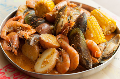 A platter of seafood including shrimp, mussels, corn, and potatoes, all seasoned and arranged appetizingly.