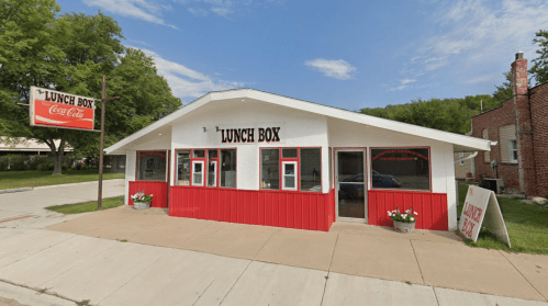 A red and white building with a sign reading "Lunch Box," featuring large windows and a welcoming entrance.