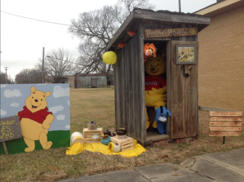A whimsical display featuring a wooden shed labeled "Pooh House," with Winnie the Pooh and friends outside.