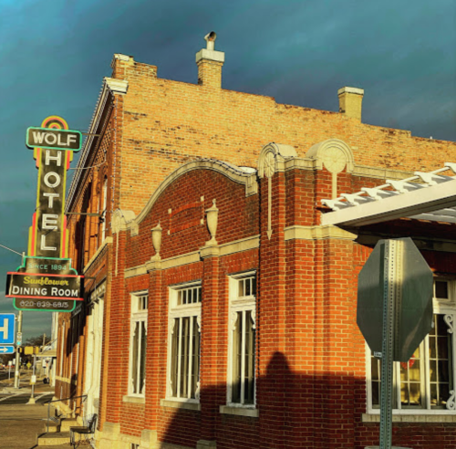 Historic brick building with a sign reading "Wolf Hotel" and a dining room, under a dramatic sky.