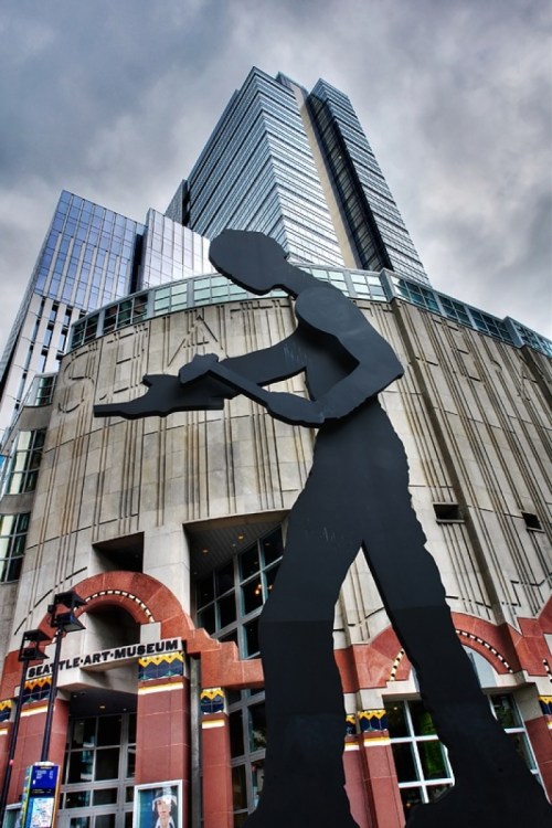 A large silhouette sculpture stands in front of the Seattle Art Museum, with modern buildings in the background.