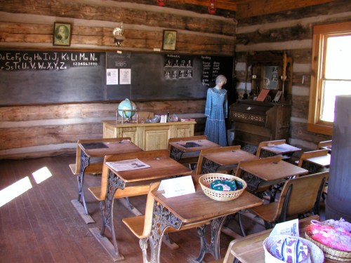 A vintage classroom with wooden desks, a chalkboard, and an antique piano, featuring a historical figure in period clothing.