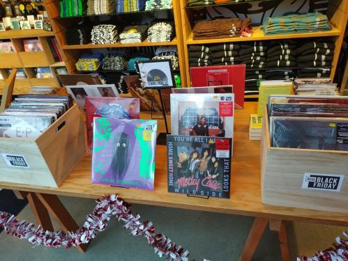 A display of vinyl records on a wooden table in a store, with various album covers visible.