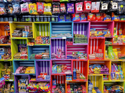 Colorful display of assorted candies and snacks in vibrant shelves, featuring various brands and types of sweets.