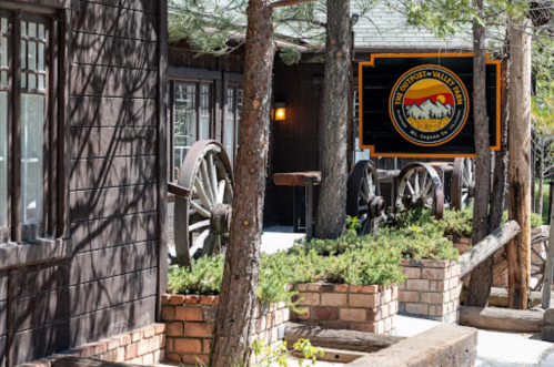 A rustic building with wooden accents, surrounded by trees and featuring a sign for "The Outpost - Willow Park."