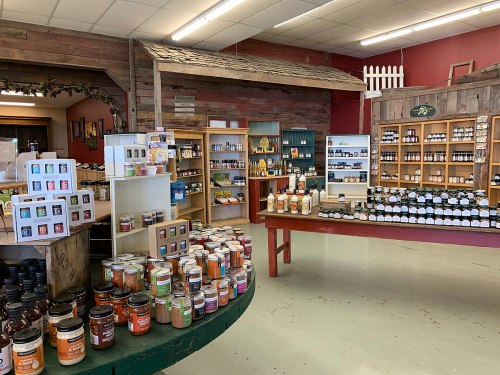 A cozy store interior filled with shelves of jars, bottles, and various products, featuring wooden decor and warm colors.