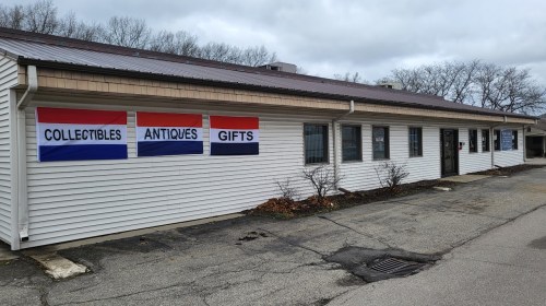 Exterior of a building with signs reading "Collectibles," "Antiques," and "Gifts" on a cloudy day.