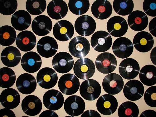 A wall covered with various vinyl records in different colors and labels, creating a vibrant, retro display.