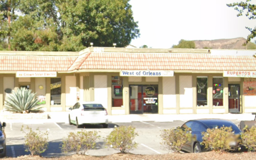 A storefront with signs for "West of Orleans" and "Ruperto's," surrounded by parking and greenery.