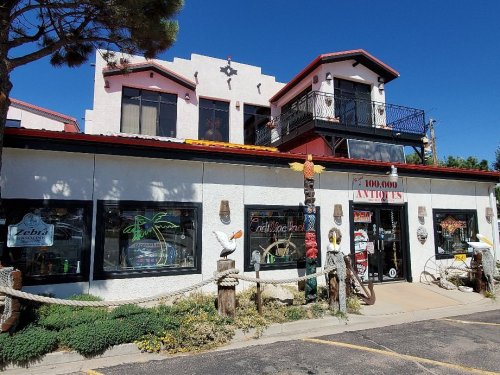 A colorful antique shop with a balcony, featuring decorative signs and tropical-themed decor outside.