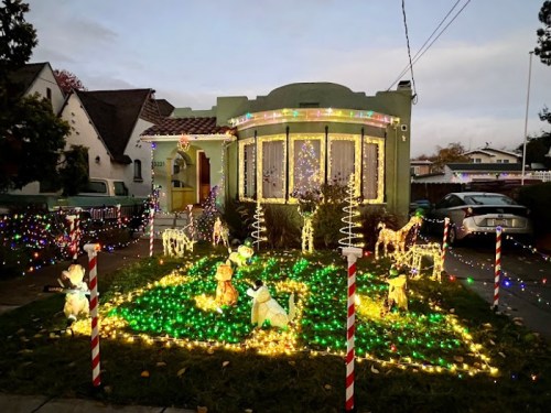 A festive house decorated with colorful lights and illuminated reindeer on the lawn, creating a cheerful holiday scene.