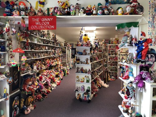 A colorful collection of clowns and toys displayed on shelves in a bright, cheerful room.
